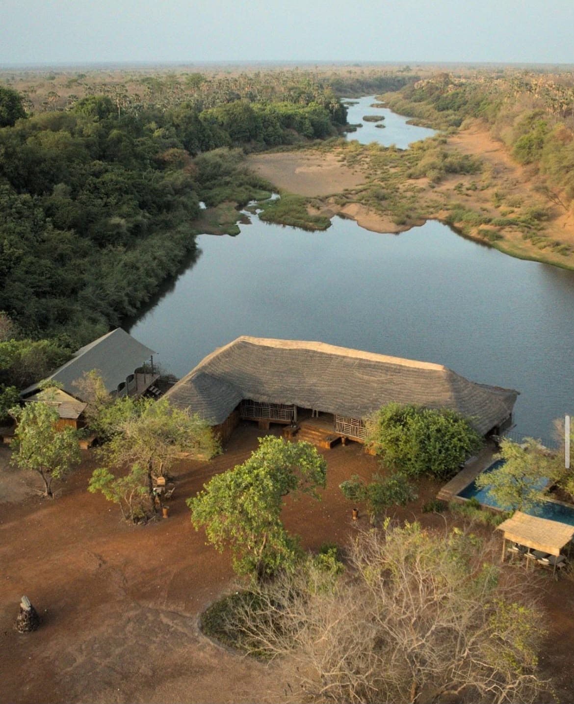 Vue aérienne de Niokolodge et de son grand toit de chaume au bord du fleuve Gambie