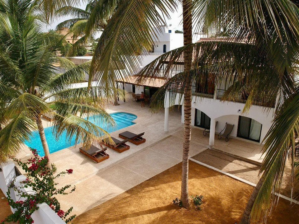 Villa blanche à étage avec piscine et terrasse, vue en hauteur entre les palmiers
